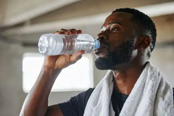 Image of man drinking water to improve hydration Leeds after work out.